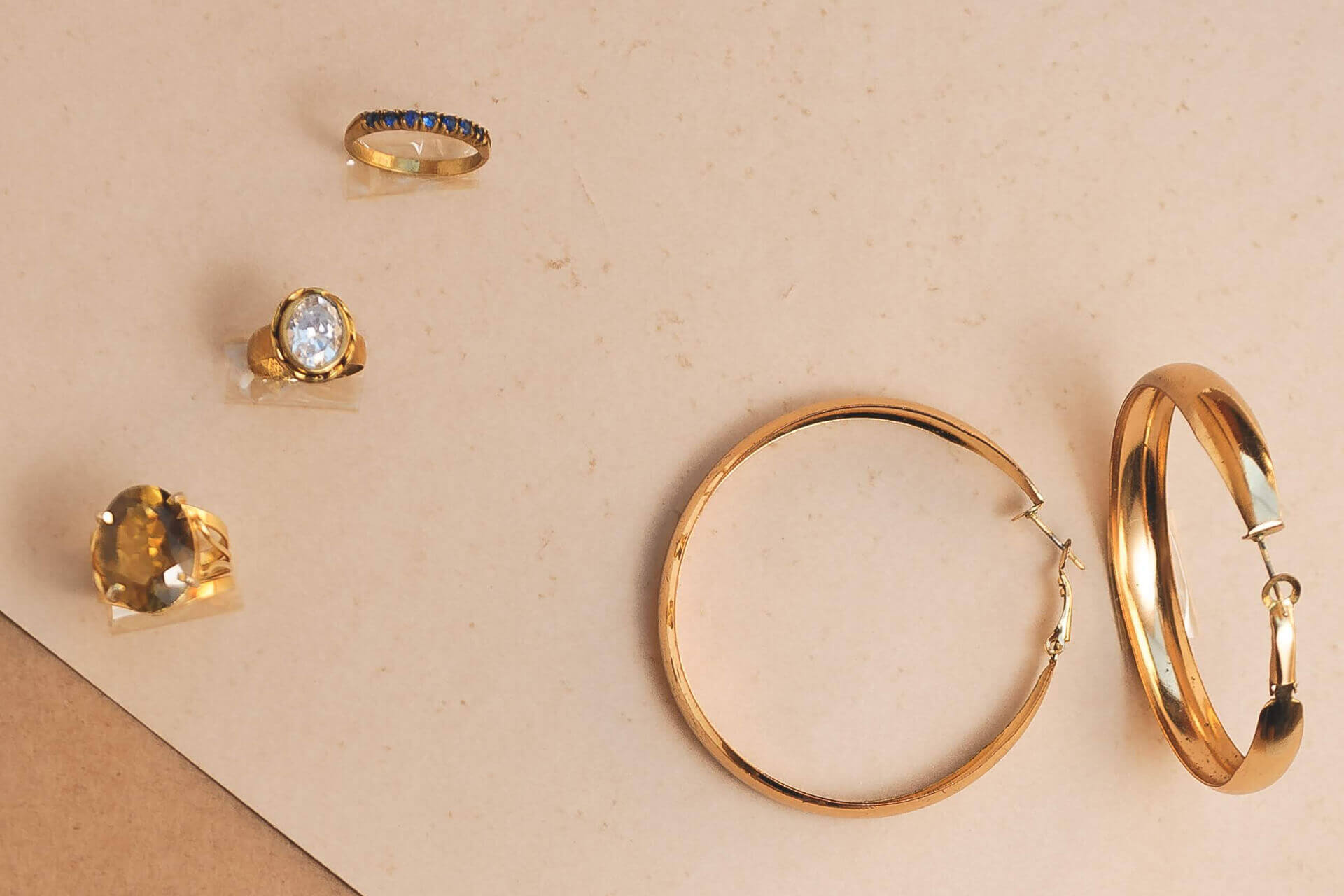 Handgefertigte Schmuckstücke wie goldene Ringe und Armreifen mit eingearbeiteten Edelsteinen auf einem Samttuch präsentiert.