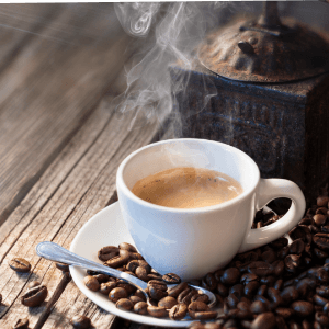 Eine dampfende Tasse Kaffee steht inmitten von verstreuten Kaffeebohnen, symbolisierend frische Zubereitung und Genuss.