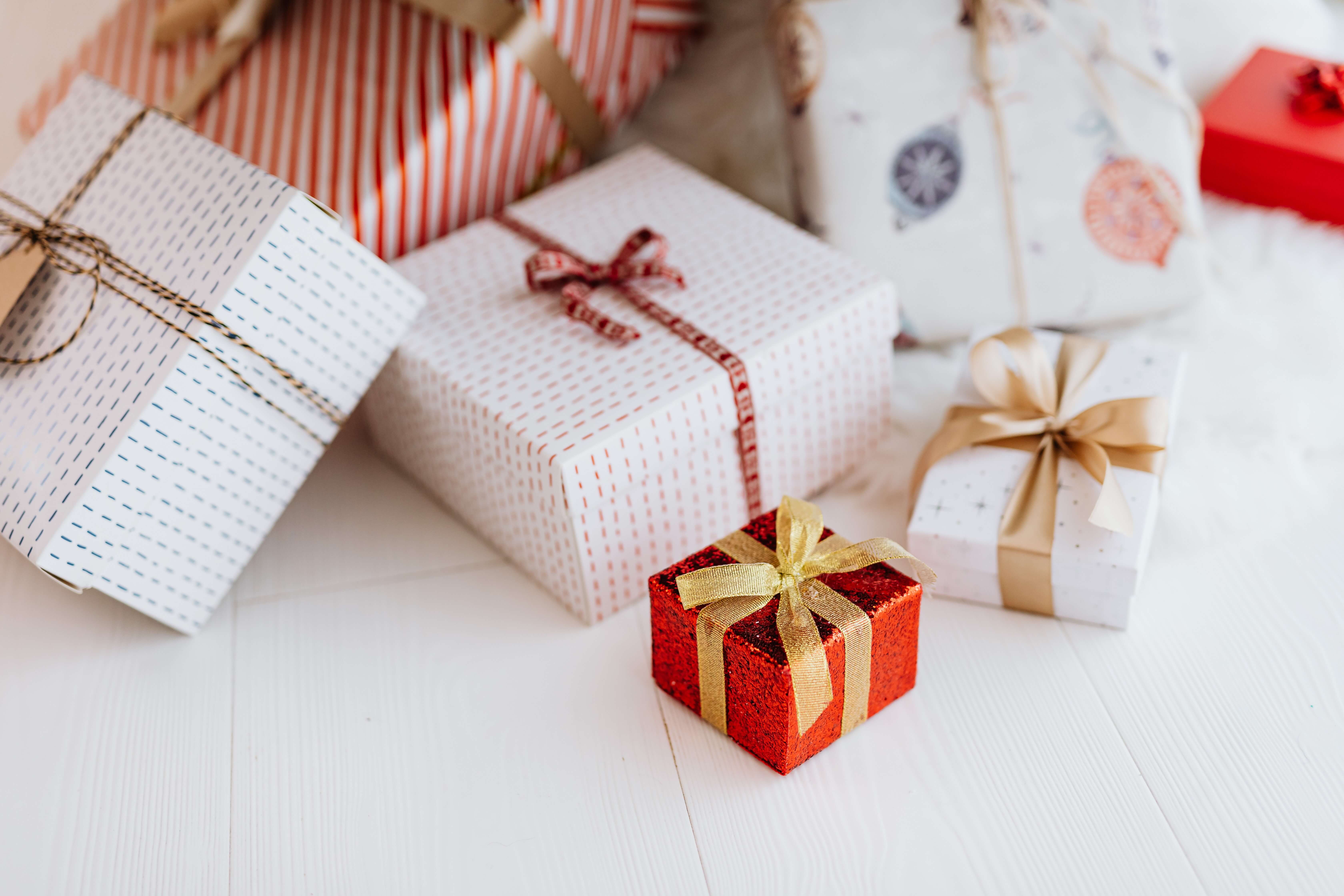 Verschiedene Geschenkverpackungen in unterschiedlichen Größen, eingewickelt in vielfältigem Geschenkpapier und verziert mit bunten Schleifenbändern